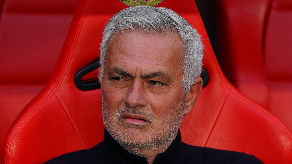 - 香港Gameone娛樂城全新會員福利 - 入金00即返送00! Close-up of a grey-haired man with stubble sitting in a red stadium seat, wearing a black top, with a wary expression.